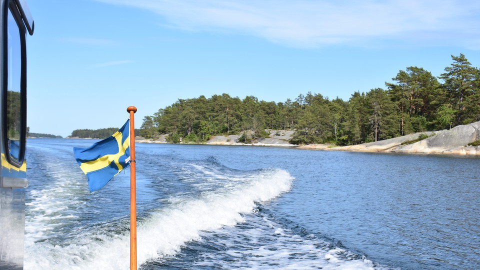 Bilden föreställer svallvågor efter en motorbåt med en svensk flagga i aktern.