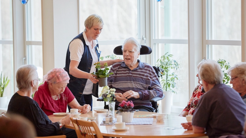 Fem äldre personer runt ett bord och en medelålders står bredvid en av de äldre.